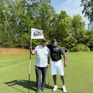 Azim Rashid and teammate at Alum Apparel flag sign